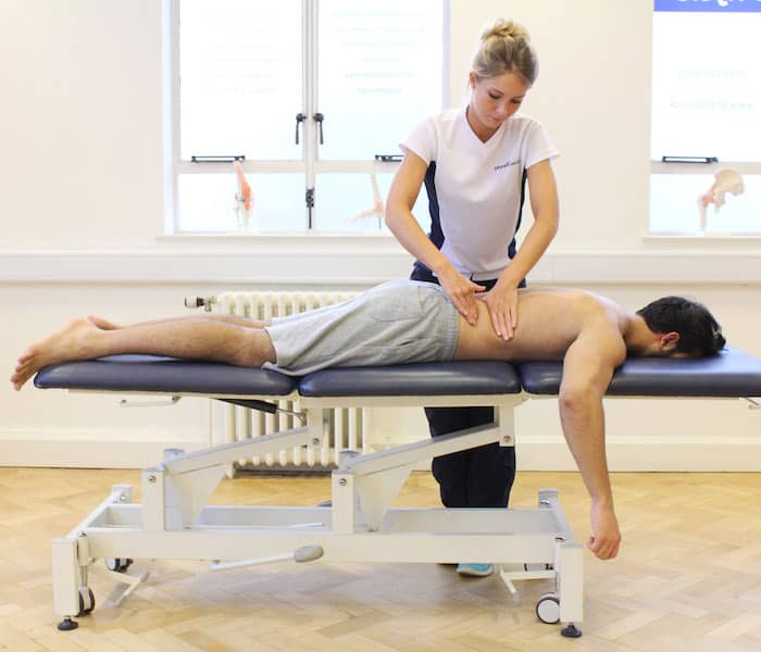 Wide shot of man lying face down with therapist giving him a massage on his back.